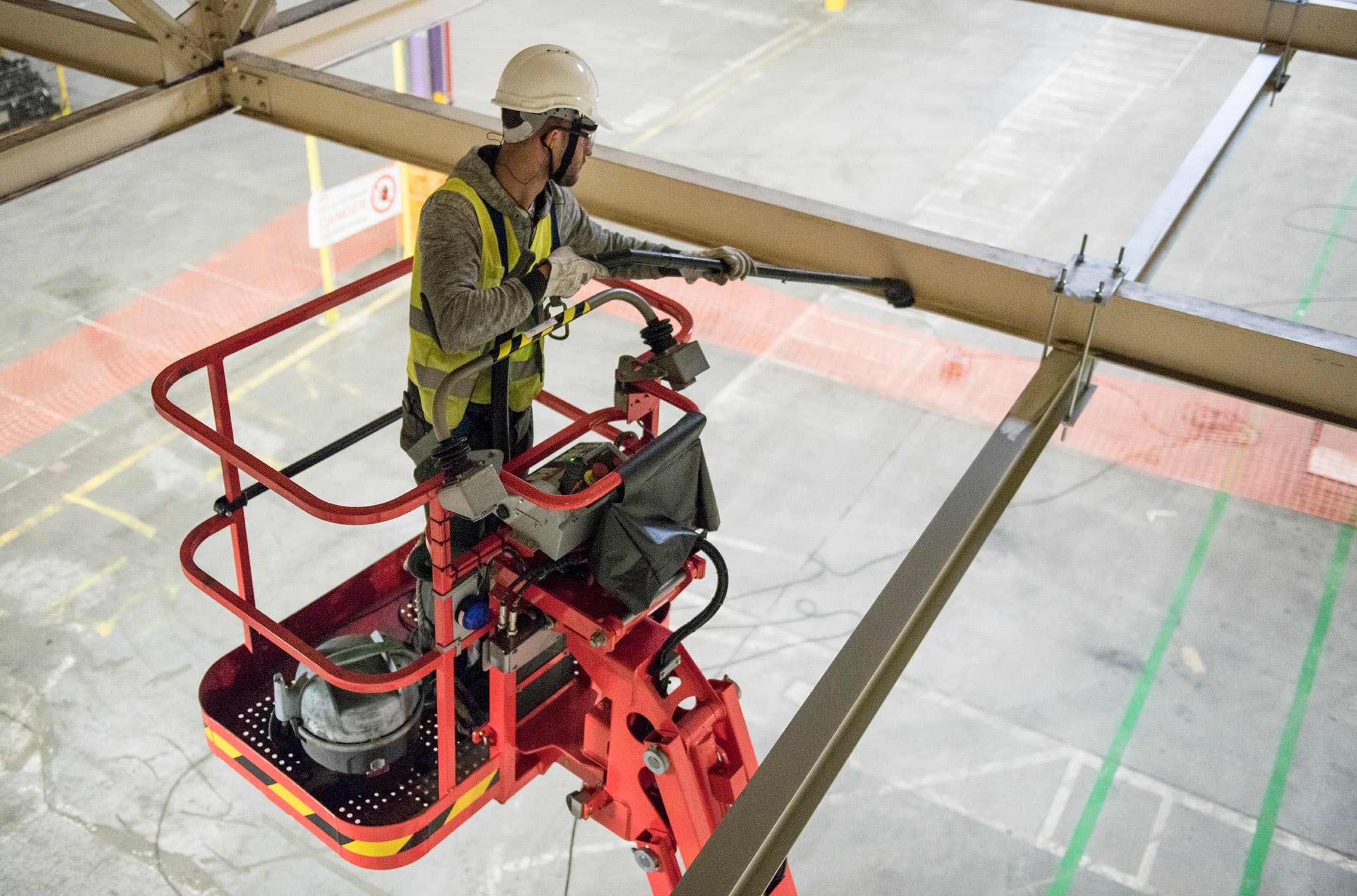 Technicien GSF en nacelle, intervenant sur une structure en hauteur dans un hall.