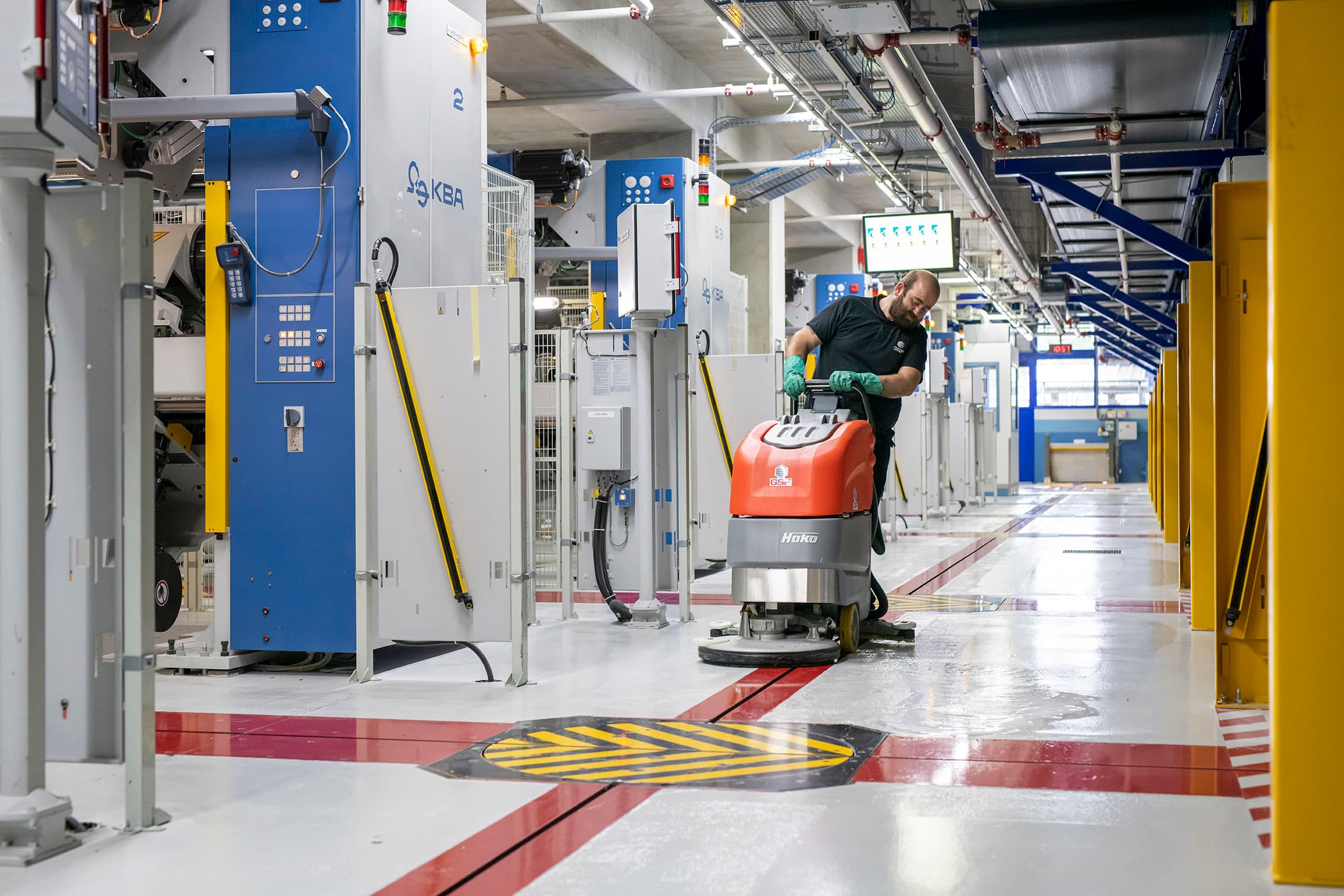 Intervenant GSF passant une autolaveuse dans une allée d’atelier.