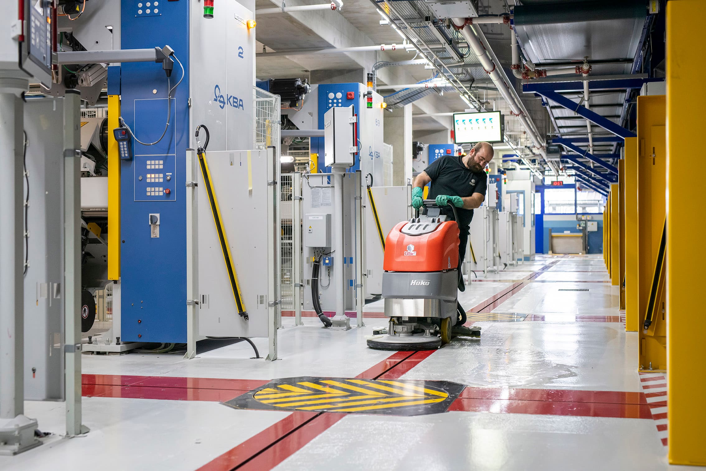 GSF team member running a floor scrubber down a workshop aisle.