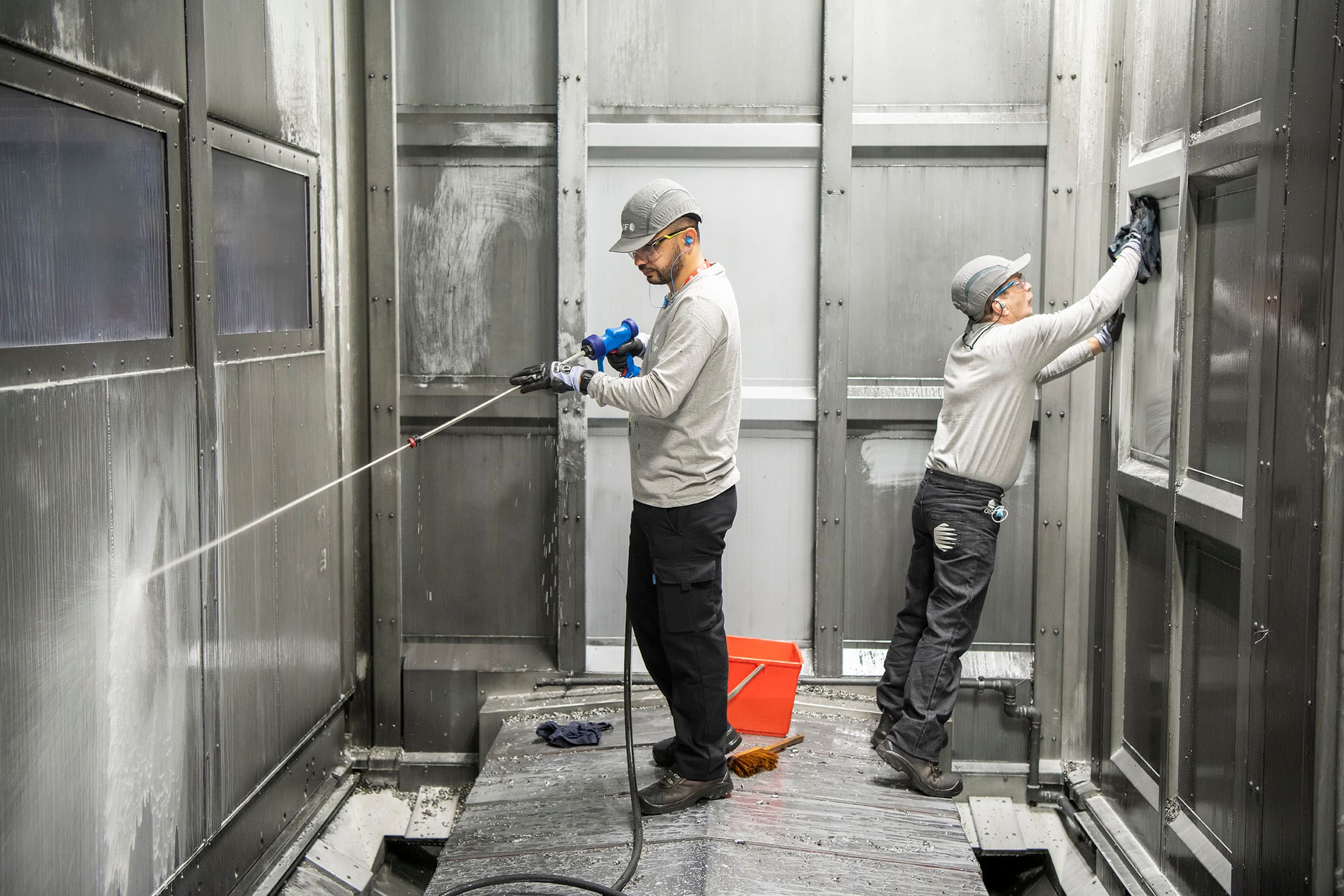 Deux intervenants GSF nettoyant l’intérieur d’une cabine de production.